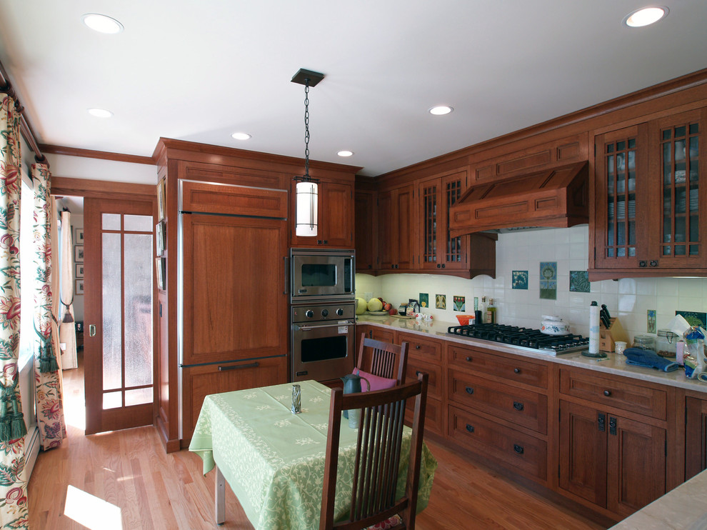 Exempel på ett avskilt, mellanstort amerikanskt u-kök, med en undermonterad diskho, luckor med infälld panel, skåp i mellenmörkt trä, bänkskiva i kalksten, gult stänkskydd, stänkskydd i keramik, integrerade vitvaror, ljust trägolv och beiget golv