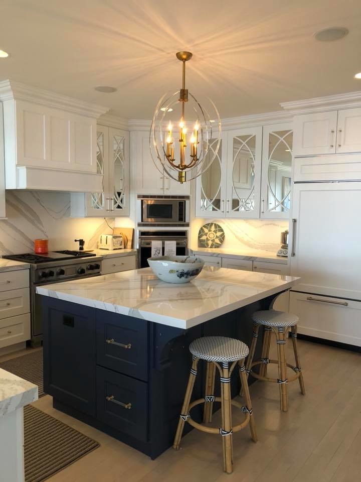 Medium sized traditional u-shaped kitchen/diner in Milwaukee with a single-bowl sink, glass-front cabinets, white cabinets, engineered stone countertops, grey splashback, marble splashback, stainless steel appliances, painted wood flooring, an island, beige floors and white worktops.