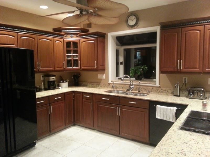 Foto di una cucina american style con ante in legno scuro, paraspruzzi beige, elettrodomestici neri, nessuna isola e pavimento marrone