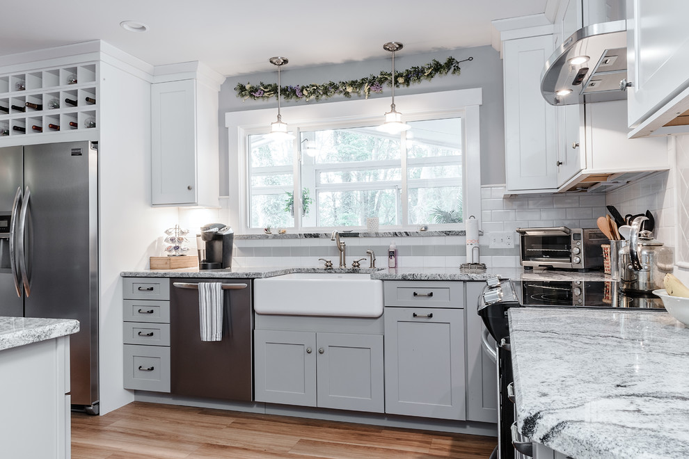 Inspiration for a mid-sized timeless u-shaped medium tone wood floor kitchen pantry remodel in Providence with a farmhouse sink, shaker cabinets, gray cabinets, granite countertops, white backsplash, subway tile backsplash and stainless steel appliances