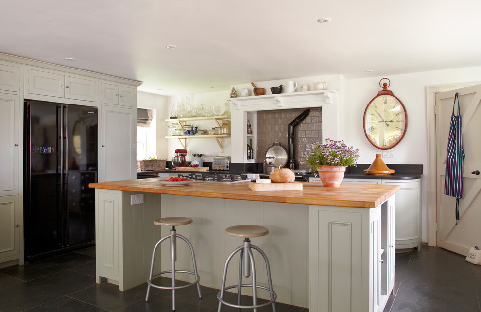 Inspiration for a country u-shaped kitchen/diner in Wiltshire with a belfast sink, recessed-panel cabinets, grey cabinets, wood worktops, grey splashback, ceramic splashback, black appliances, slate flooring and an island.