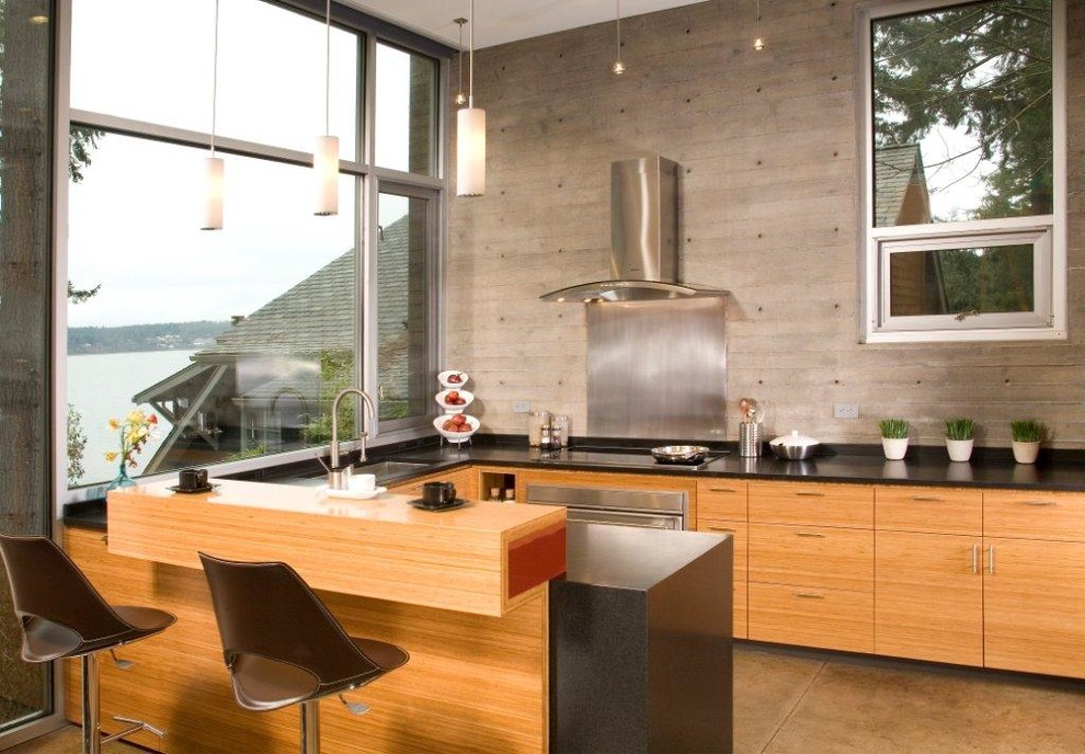 This is an example of a contemporary u-shaped open plan kitchen in Seattle with stainless steel appliances, a single-bowl sink, beige cabinets, concrete flooring, grey floors and black worktops.