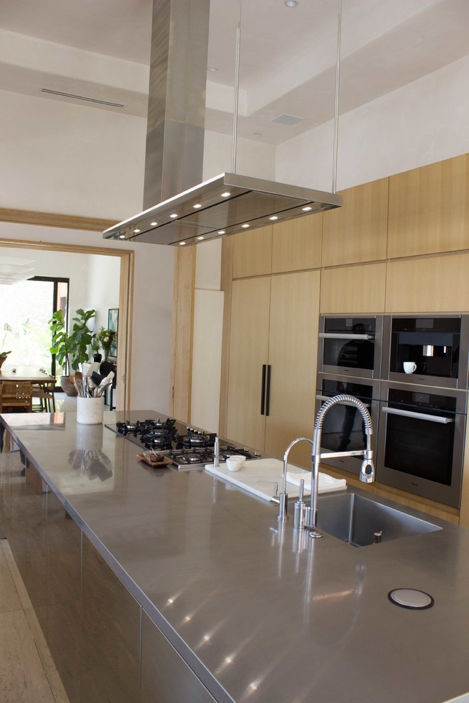 Foto på ett stort funkis linjärt kök med öppen planlösning, med en integrerad diskho, släta luckor, skåp i rostfritt stål, bänkskiva i rostfritt stål, flera köksöar och beiget golv