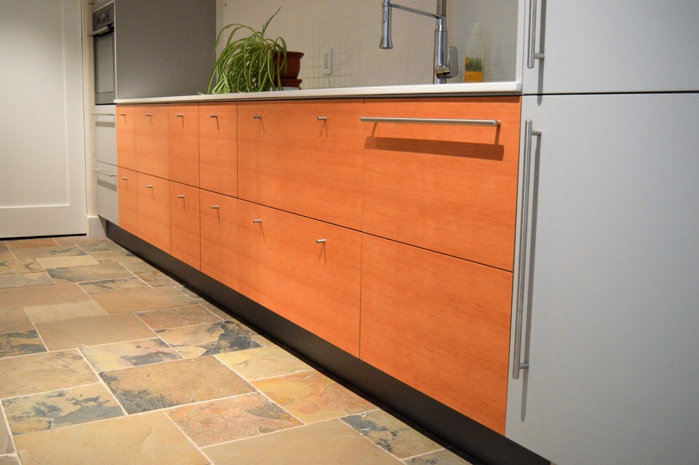 Example of a mid-sized minimalist galley slate floor and multicolored floor enclosed kitchen design in Toronto with an undermount sink, flat-panel cabinets, light wood cabinets, quartz countertops, white backsplash, ceramic backsplash and white countertops