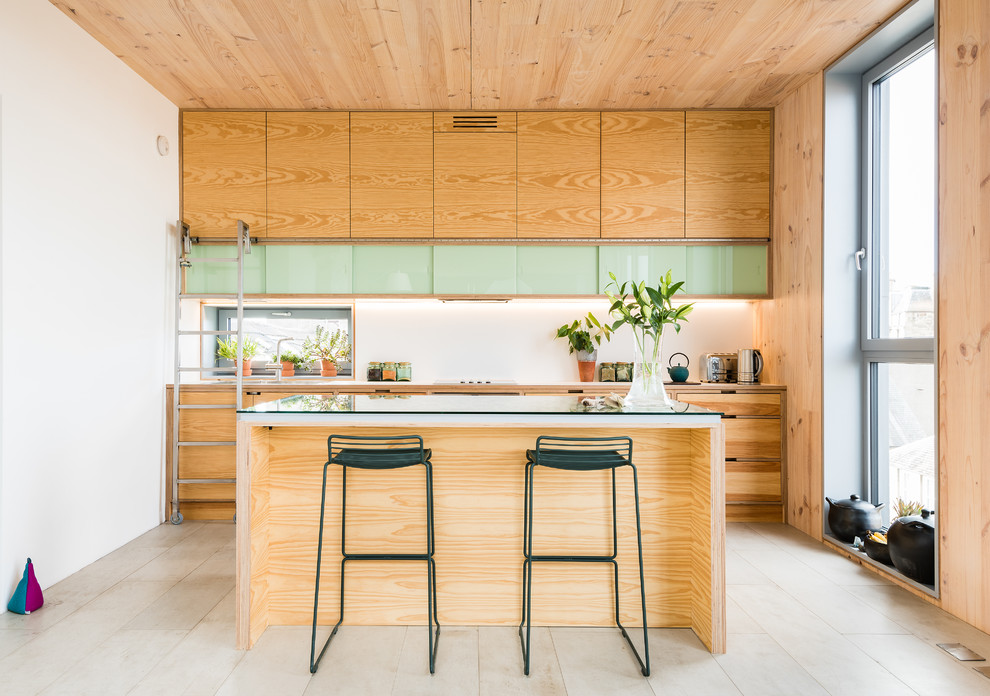 Exemple d'une cuisine linéaire tendance en bois clair de taille moyenne avec îlot, un placard à porte plane, un plan de travail en verre et un sol beige.