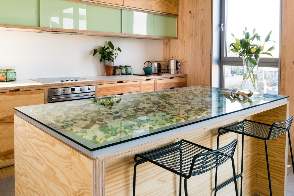Inspiration for a medium sized contemporary single-wall kitchen in Edinburgh with stainless steel appliances, an island, flat-panel cabinets, glass worktops, multicoloured worktops and light wood cabinets.