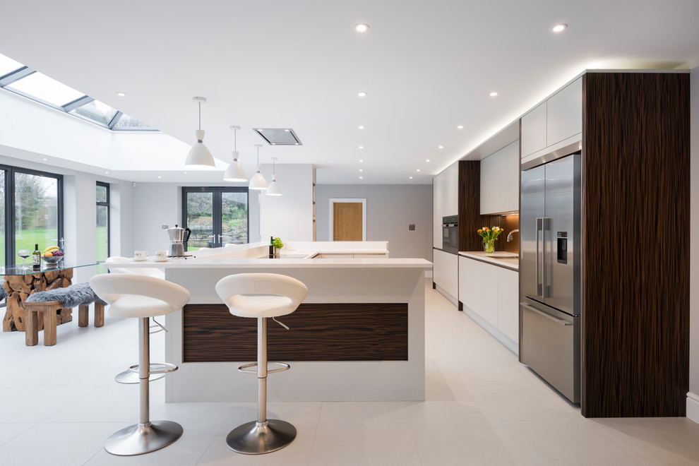 Große Moderne Küche in U-Form mit flächenbündigen Schrankfronten, grauen Schränken, Küchengeräten aus Edelstahl, Kücheninsel, grauem Boden und weißer Arbeitsplatte in Kent