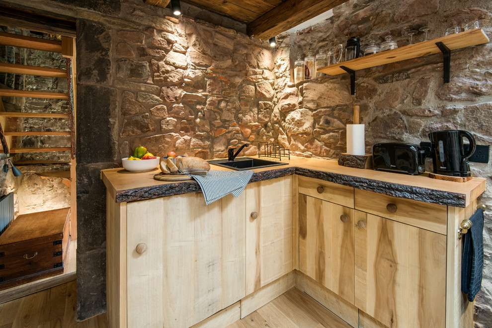 Exemple d'une petite cuisine américaine nature en bois brun et L avec un évier posé, un placard à porte plane, un plan de travail en bois, un sol en bois brun et aucun îlot.