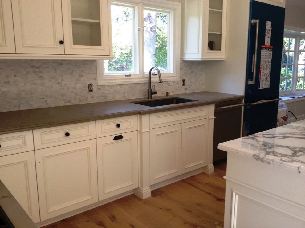 Idéer för att renovera ett funkis kök, med en undermonterad diskho, luckor med infälld panel, vita skåp, marmorbänkskiva, stänkskydd i stenkakel, rostfria vitvaror, ljust trägolv och en köksö