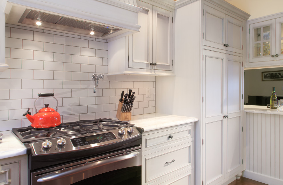 Exempel på ett mellanstort klassiskt kök, med en rustik diskho, luckor med profilerade fronter, grå skåp, marmorbänkskiva, vitt stänkskydd, stänkskydd i tunnelbanekakel, rostfria vitvaror, mörkt trägolv, en köksö och brunt golv