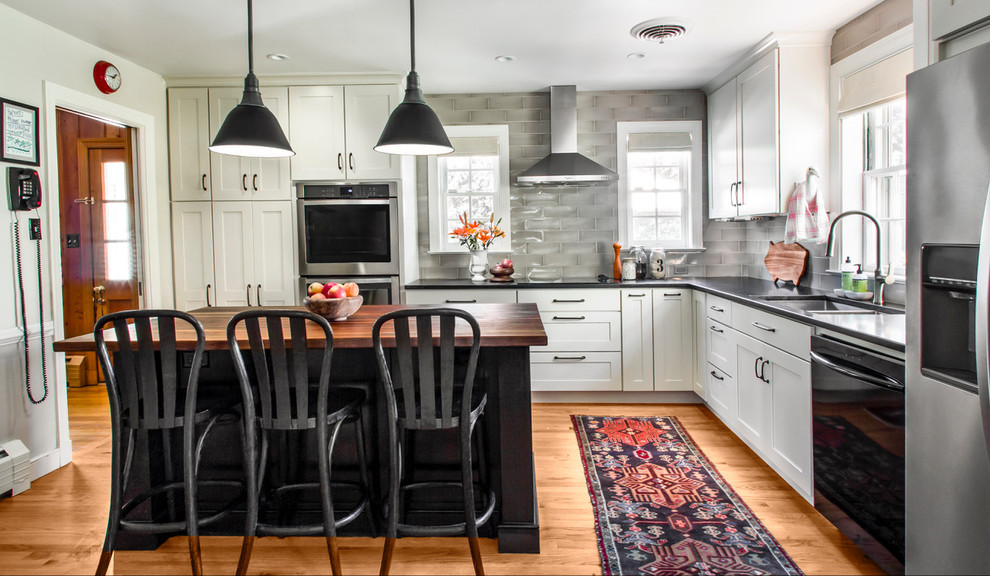 Mid-sized eclectic u-shaped medium tone wood floor and brown floor enclosed kitchen photo in Other with an undermount sink, shaker cabinets, white cabinets, wood countertops, gray backsplash, ceramic backsplash, stainless steel appliances and an island
