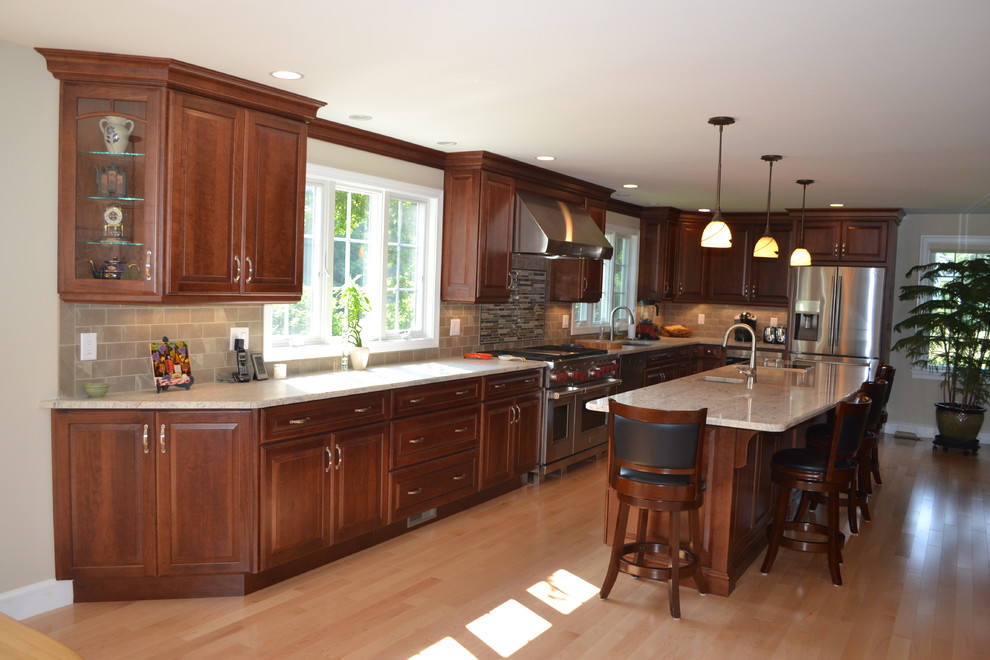 Eat-in kitchen - large traditional l-shaped light wood floor eat-in kitchen idea in Boston with an undermount sink, raised-panel cabinets, dark wood cabinets, granite countertops, metallic backsplash, ceramic backsplash, stainless steel appliances and an island