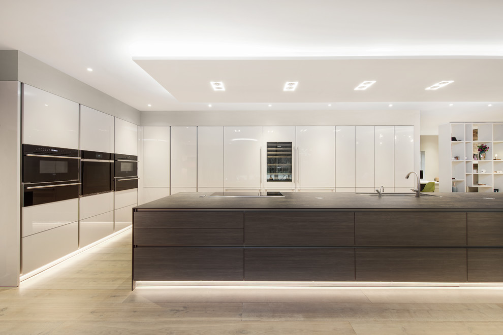 Inspiration for a large contemporary galley kitchen/diner in Hampshire with flat-panel cabinets, light wood cabinets, engineered stone countertops, stainless steel appliances and an island.