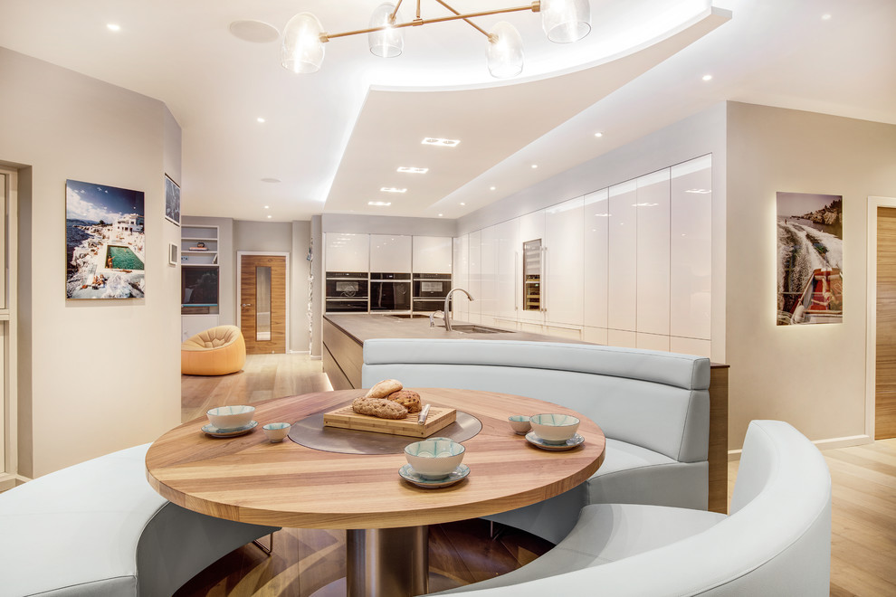 Eat-in kitchen - large contemporary galley light wood floor eat-in kitchen idea in Hampshire with an undermount sink, flat-panel cabinets, dark wood cabinets, quartz countertops, stainless steel appliances and an island