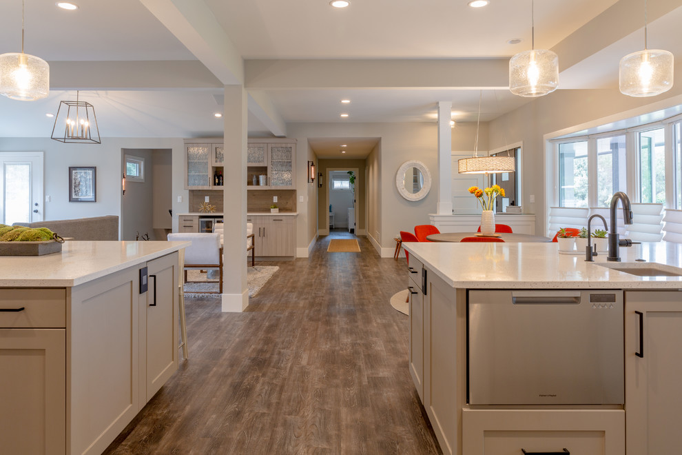 Inspiration for a large modern laminate floor and gray floor open concept kitchen remodel in Denver with a farmhouse sink, flat-panel cabinets, gray cabinets, quartz countertops, gray backsplash, porcelain backsplash, stainless steel appliances, two islands and white countertops