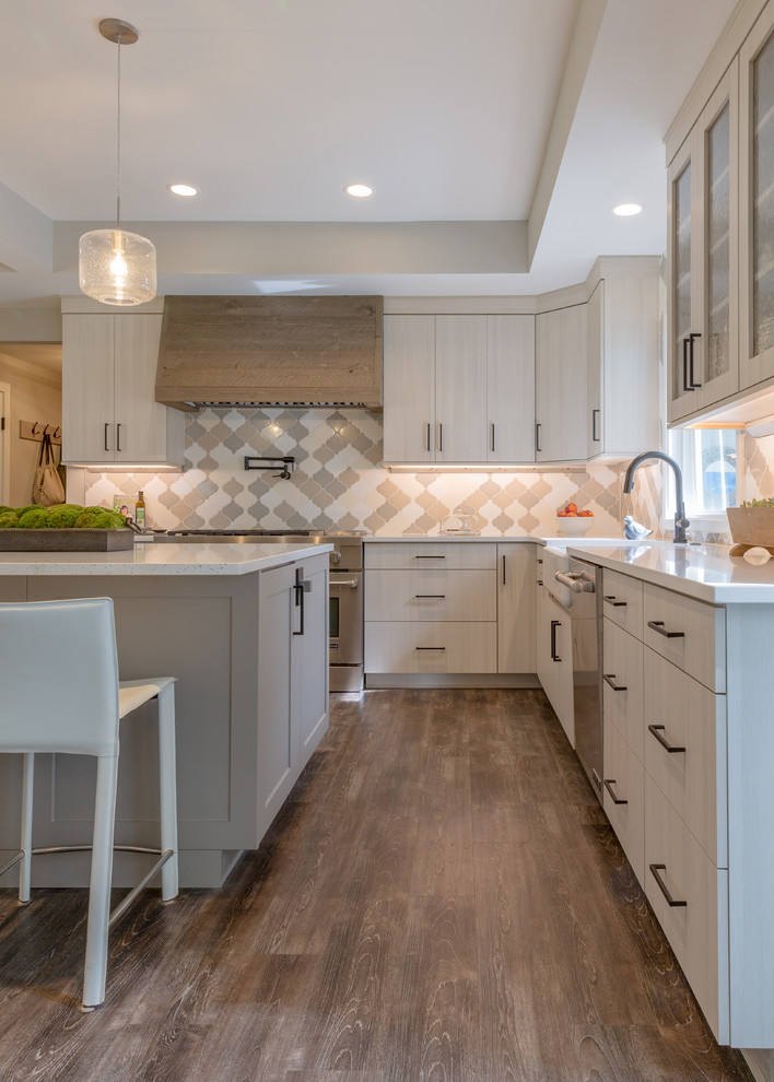 Example of a large minimalist laminate floor and gray floor open concept kitchen design in Denver with a farmhouse sink, flat-panel cabinets, gray cabinets, quartz countertops, gray backsplash, porcelain backsplash, stainless steel appliances, two islands and white countertops