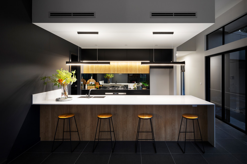 Foto på ett mellanstort funkis kök, med en undermonterad diskho, bänkskiva i kvarts, svart stänkskydd, spegel som stänkskydd, svarta vitvaror, klinkergolv i porslin, flera köksöar och svart golv