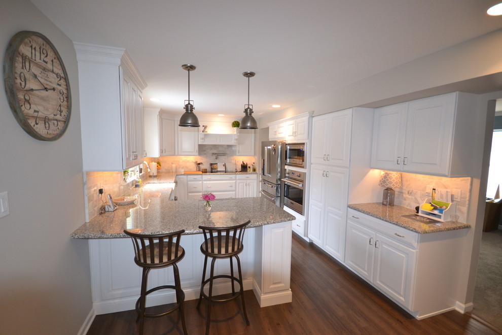 Exempel på ett stort klassiskt kök, med en rustik diskho, luckor med upphöjd panel, vita skåp, granitbänkskiva, beige stänkskydd, stänkskydd i keramik, rostfria vitvaror, mellanmörkt trägolv och en köksö