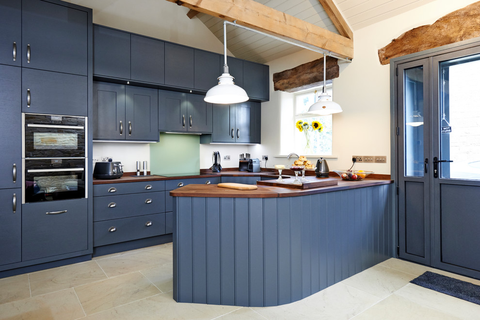 Exempel på ett lantligt u-kök, med släta luckor, blå skåp, träbänkskiva, svarta vitvaror, en halv köksö och beiget golv