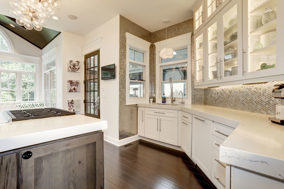 Exempel på ett mellanstort klassiskt vit vitt kök, med en undermonterad diskho, luckor med glaspanel, vita skåp, bänkskiva i onyx, stänkskydd med metallisk yta, stänkskydd i metallkakel, rostfria vitvaror, mörkt trägolv, en köksö och brunt golv
