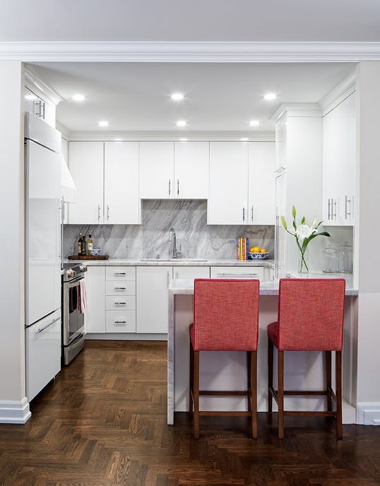 This is an example of a small traditional u-shaped kitchen/diner in Toronto with a submerged sink, flat-panel cabinets, white cabinets, marble worktops, white splashback, marble splashback, integrated appliances, dark hardwood flooring, brown floors and a breakfast bar.