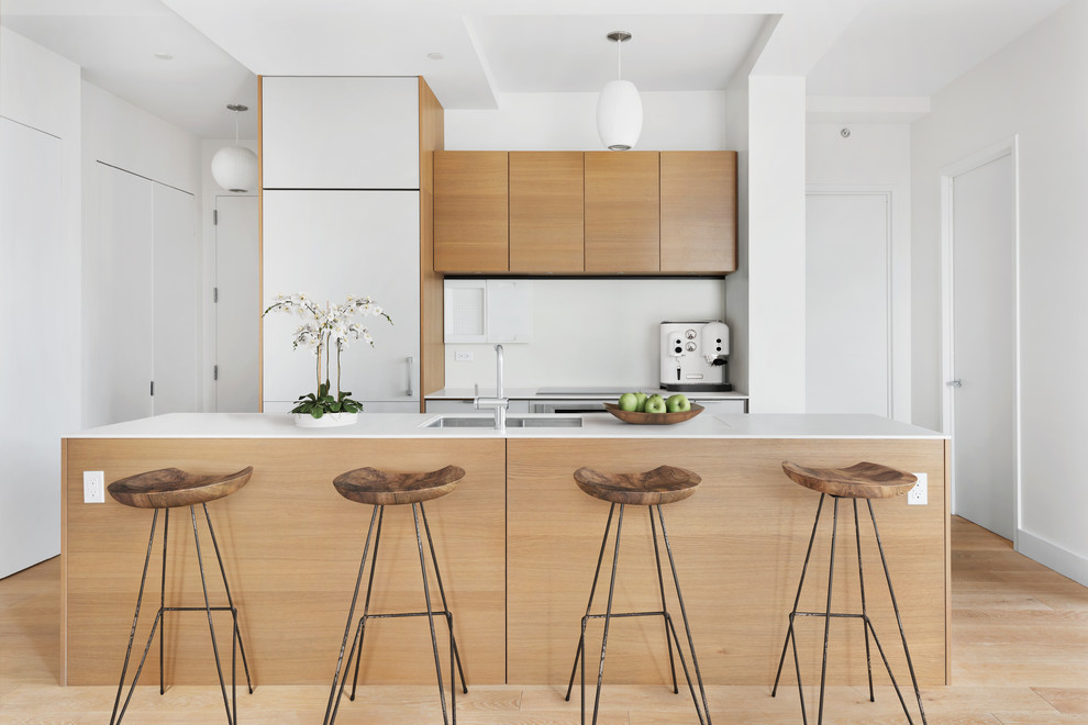 Esempio di una cucina design di medie dimensioni con lavello sottopiano, ante lisce, ante in legno chiaro, elettrodomestici da incasso, parquet chiaro, top bianco e pavimento marrone