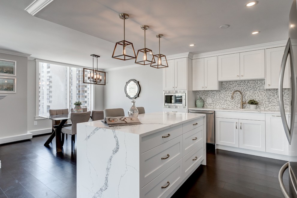 Inspiration for a mid-sized transitional l-shaped dark wood floor and brown floor eat-in kitchen remodel in Calgary with an undermount sink, shaker cabinets, white cabinets, quartz countertops, multicolored backsplash, marble backsplash, stainless steel appliances, an island and white countertops