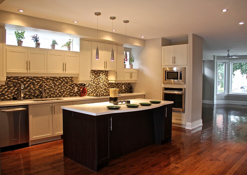 Mid-sized minimalist u-shaped medium tone wood floor open concept kitchen photo in Toronto with an undermount sink, shaker cabinets, white cabinets, quartz countertops, multicolored backsplash, glass tile backsplash, stainless steel appliances and an island