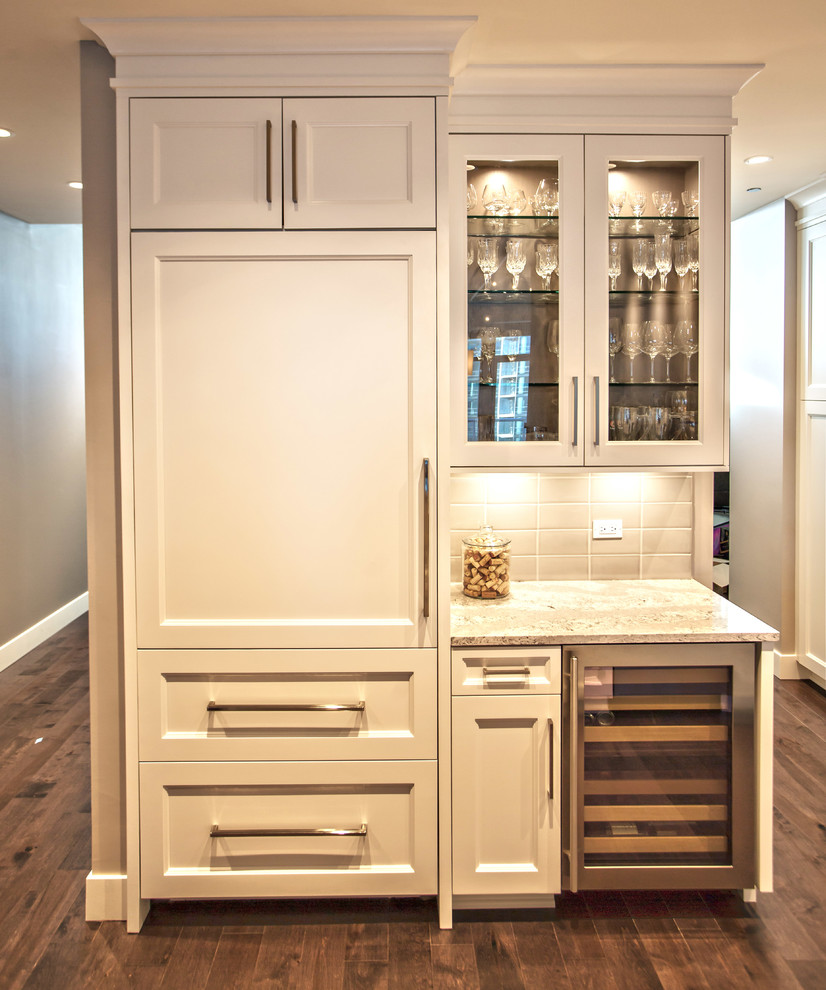 Klassisk inredning av ett mellanstort grå grått kök, med en dubbel diskho, luckor med infälld panel, vita skåp, bänkskiva i kvartsit, grått stänkskydd, stänkskydd i keramik, integrerade vitvaror, mellanmörkt trägolv, en halv köksö och brunt golv