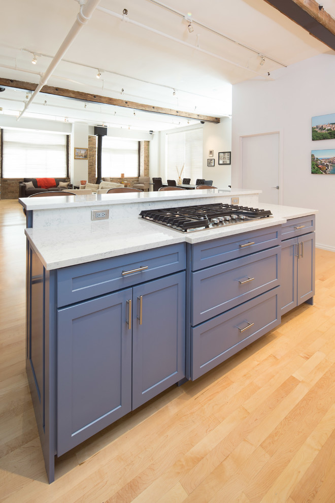 Mid-sized minimalist l-shaped light wood floor eat-in kitchen photo in Chicago with a farmhouse sink, shaker cabinets, blue cabinets, white backsplash, stainless steel appliances, an island, granite countertops and subway tile backsplash