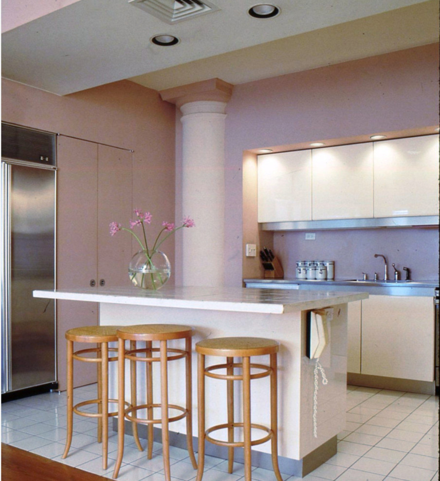 Example of a large minimalist u-shaped ceramic tile and white floor kitchen pantry design in New York with a drop-in sink, flat-panel cabinets, white cabinets, pink backsplash, stainless steel appliances, an island, tile countertops and glass tile backsplash