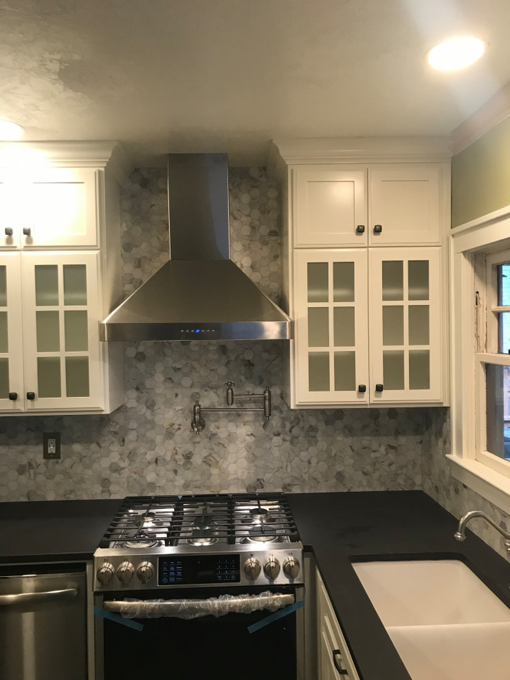 Inspiration for a small timeless l-shaped vinyl floor and black floor eat-in kitchen remodel in Portland with an undermount sink, glass-front cabinets, white cabinets, quartzite countertops, gray backsplash, stone tile backsplash, stainless steel appliances, a peninsula and black countertops
