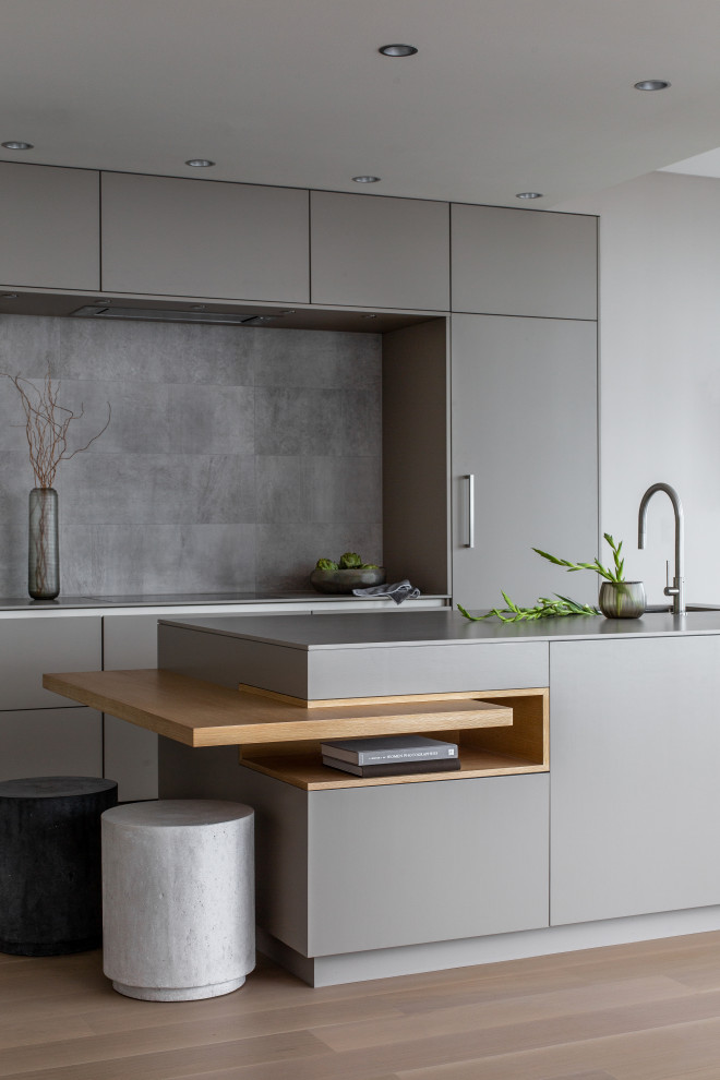 Modern inredning av ett grå grått kök och matrum, med en undermonterad diskho, släta luckor, grå skåp, bänkskiva i kvarts, grått stänkskydd, integrerade vitvaror, mellanmörkt trägolv, en köksö och brunt golv