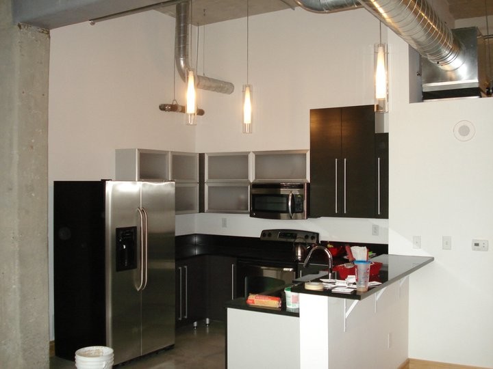 This is an example of a small industrial u-shaped kitchen in Kansas City with a belfast sink, flat-panel cabinets, grey cabinets, composite countertops, red splashback, stainless steel appliances, concrete flooring and no island.