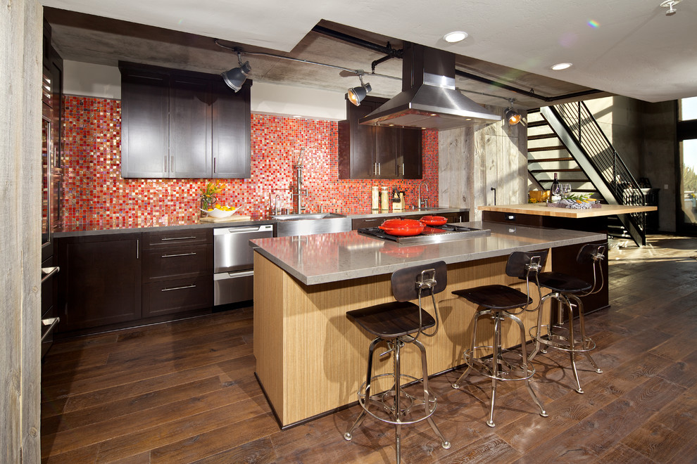 Contemporary kitchen in San Diego with a belfast sink, engineered stone countertops, red splashback, stainless steel appliances, dark hardwood flooring and an island.