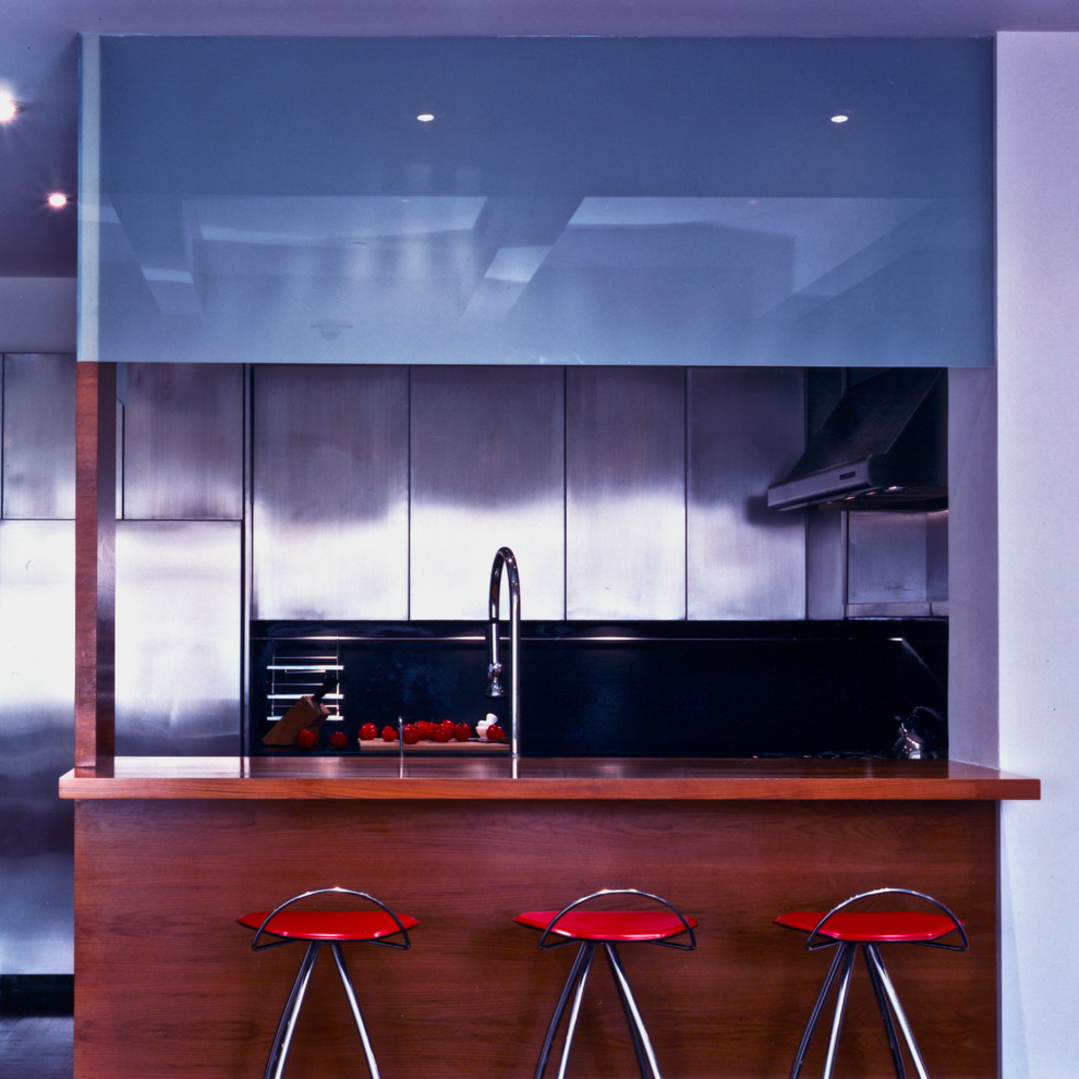 Small u-shaped kitchen/diner in Portland with a double-bowl sink, flat-panel cabinets, stainless steel cabinets, granite worktops, black splashback, stone slab splashback, stainless steel appliances, dark hardwood flooring, no island, brown floors and black worktops.