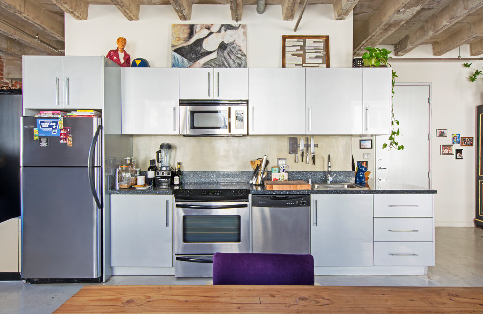 Cette image montre une cuisine ouverte linéaire urbaine avec un évier posé, un placard à porte plane, une crédence beige, un électroménager en acier inoxydable et aucun îlot.