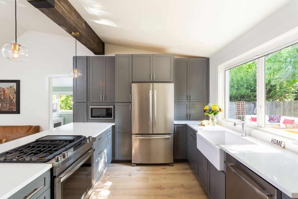 Photo of a medium sized classic u-shaped kitchen/diner in Denver with shaker cabinets, grey cabinets, engineered stone countertops, stainless steel appliances, medium hardwood flooring, a breakfast bar and white worktops.