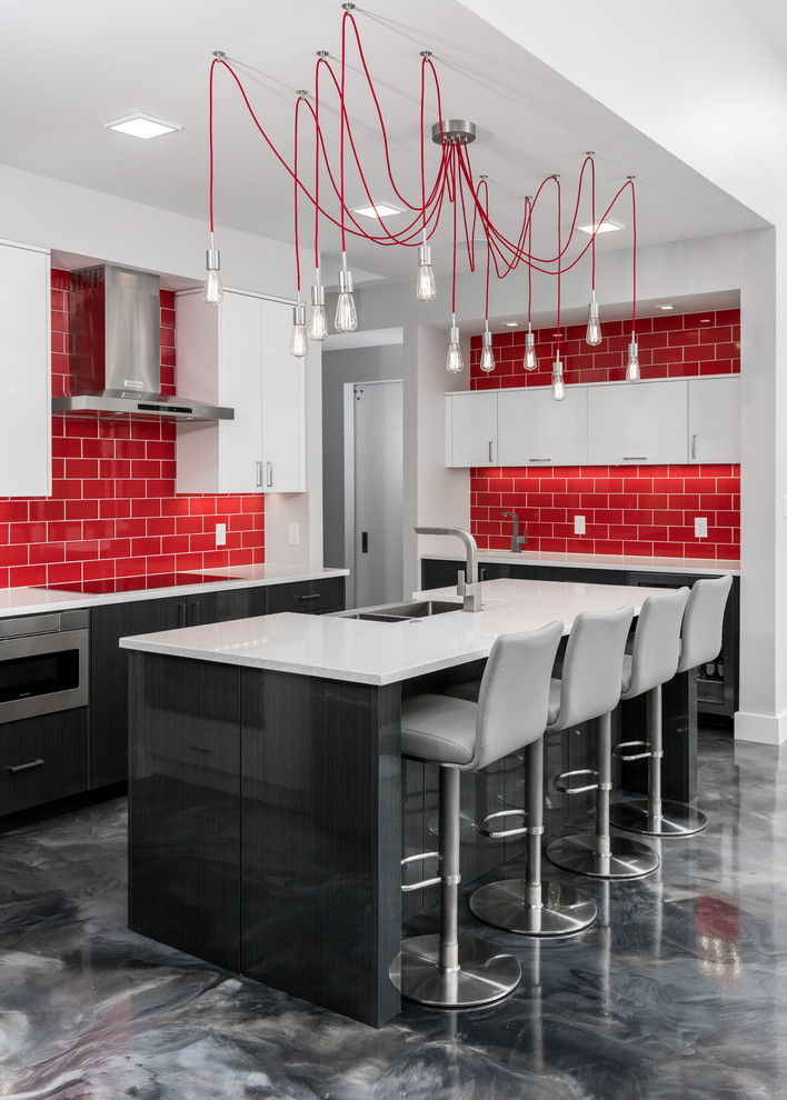 Bild på ett mellanstort funkis kök, med en dubbel diskho, släta luckor, rött stänkskydd, stänkskydd i keramik, rostfria vitvaror, betonggolv, en köksö och grått golv