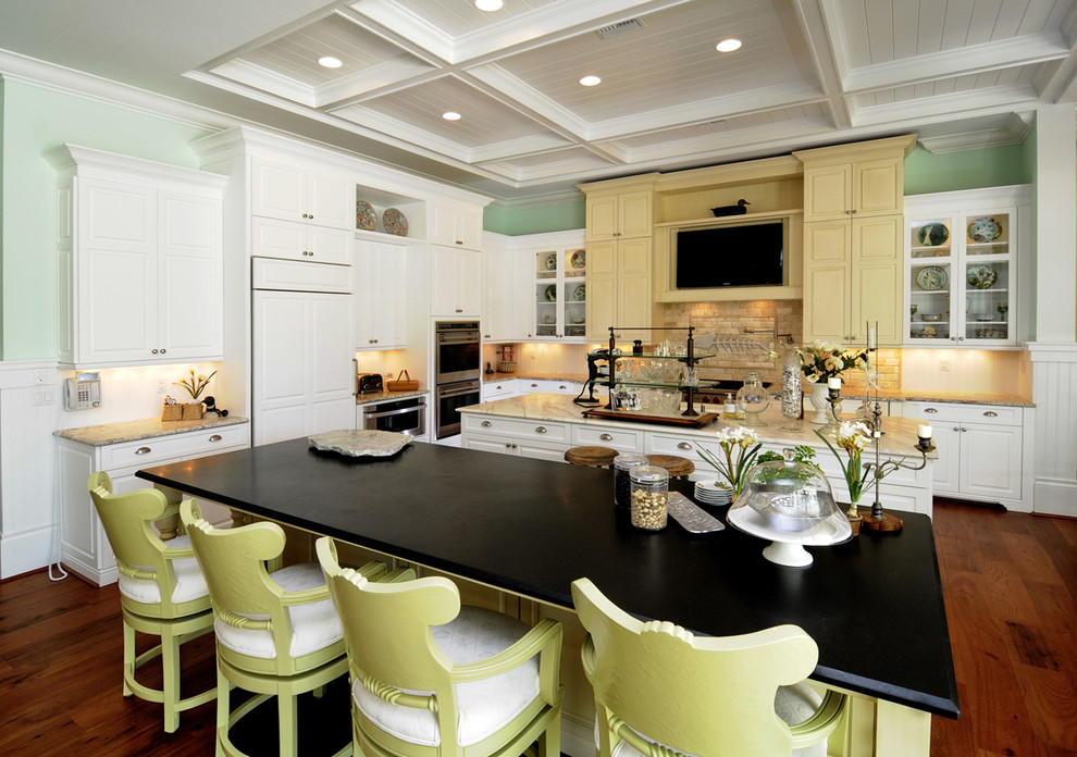 На фото: кухня в классическом стиле с фасадами с выступающей филенкой, желтыми фасадами и техникой под мебельный фасад