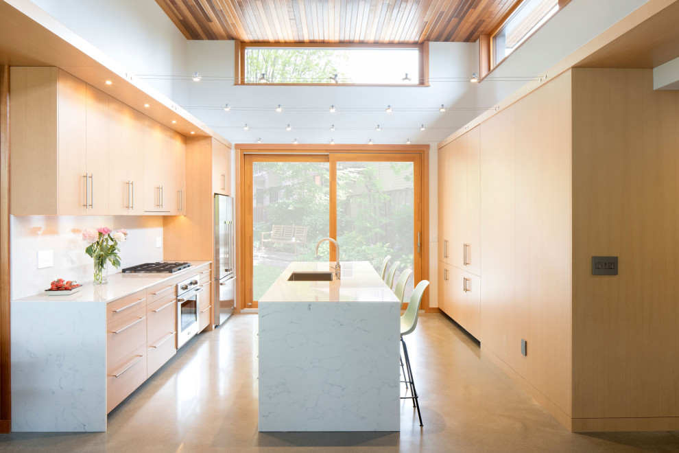 Inspiration for a mid-century modern galley concrete floor and gray floor kitchen remodel in Seattle with an undermount sink, flat-panel cabinets, light wood cabinets, stainless steel appliances, an island and white countertops