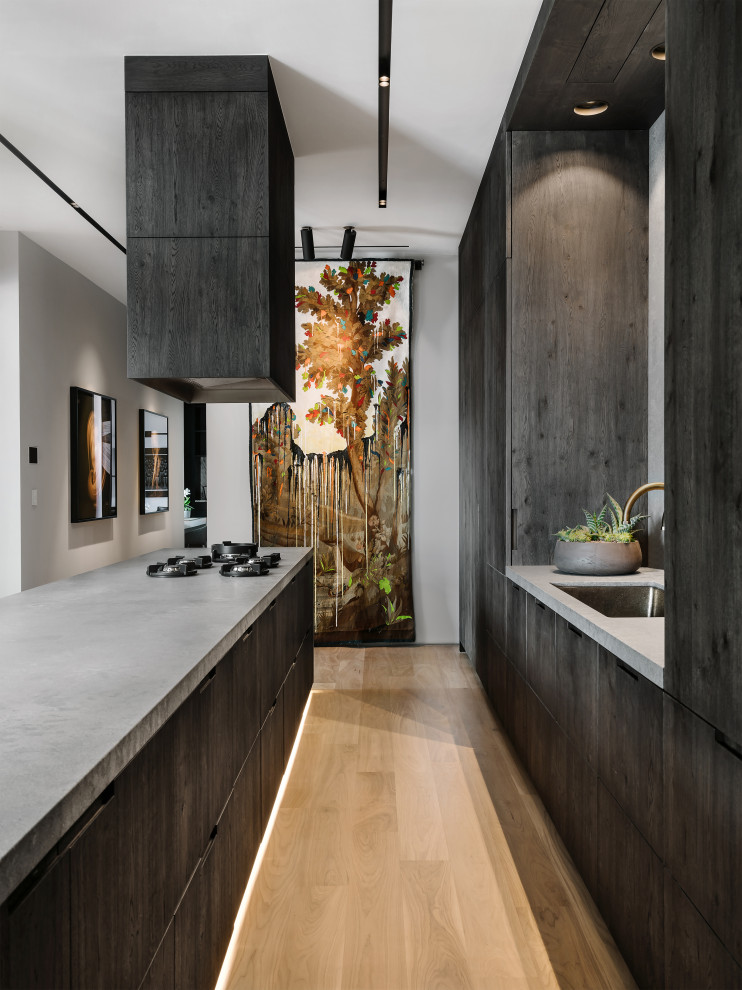 Inspiration for a contemporary single-wall kitchen remodel in Austin with a single-bowl sink, flat-panel cabinets, dark wood cabinets, gray backsplash and an island