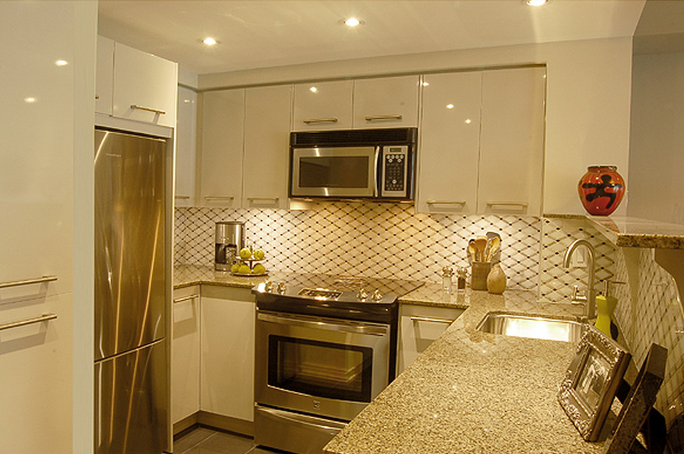 Exempel på ett litet modernt kök, med en enkel diskho, släta luckor, grå skåp, granitbänkskiva, grått stänkskydd, stänkskydd i mosaik, rostfria vitvaror, klinkergolv i porslin och en halv köksö