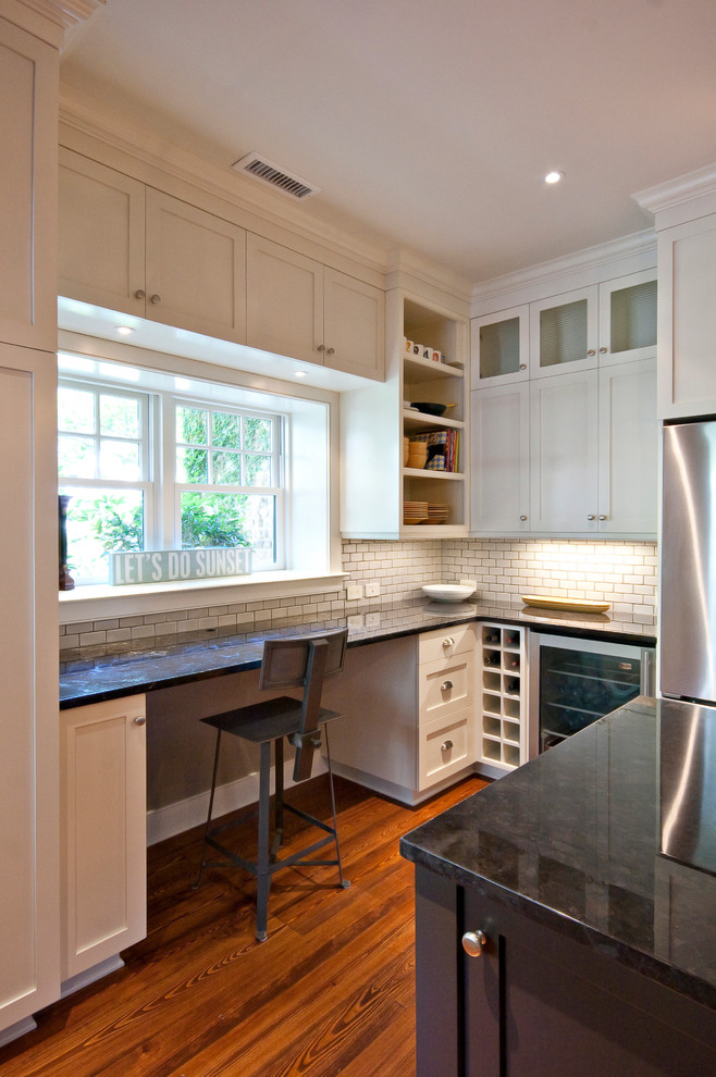 Cette photo montre une cuisine chic avec un placard à porte shaker, des portes de placard blanches, une crédence blanche et un électroménager en acier inoxydable.