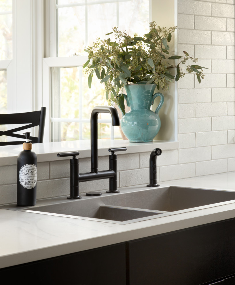 Example of a large u-shaped porcelain tile and multicolored floor open concept kitchen design in DC Metro with a drop-in sink, shaker cabinets, black cabinets, quartz countertops, white backsplash, porcelain backsplash, black appliances, a peninsula and white countertops