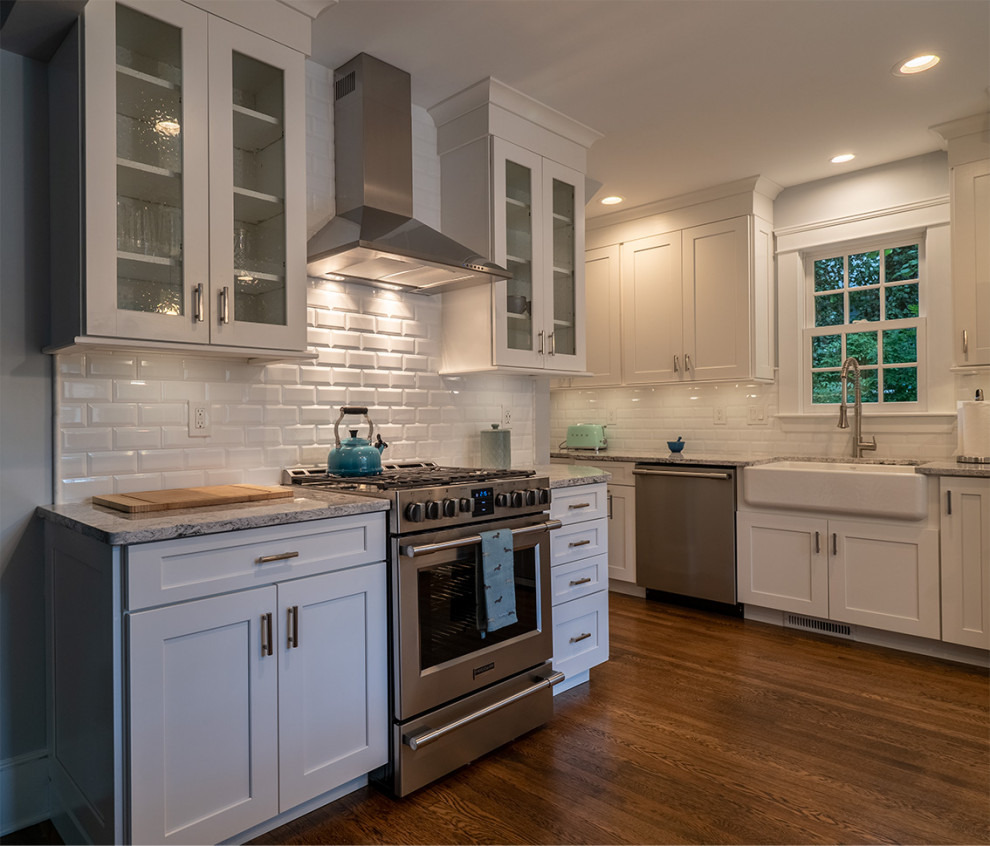 Kitchen - mid-sized traditional medium tone wood floor kitchen idea in Providence with a farmhouse sink, shaker cabinets, white cabinets, quartz countertops, white backsplash, subway tile backsplash, stainless steel appliances, an island and white countertops