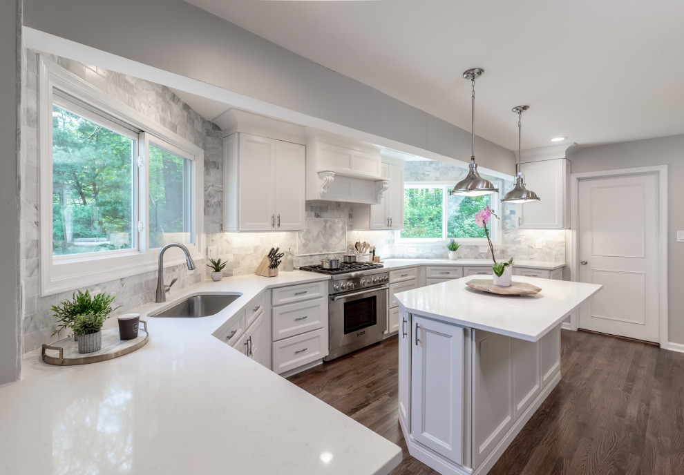 Bild på ett mellanstort funkis vit vitt kök och matrum, med vita skåp, granitbänkskiva, grått stänkskydd, rostfria vitvaror, en köksö och brunt golv