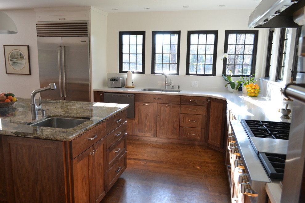 Foto på ett stort vintage vit l-kök, med skåp i shakerstil, skåp i mellenmörkt trä, bänkskiva i kvarts, stänkskydd med metallisk yta, stänkskydd i glaskakel, vita vitvaror, mellanmörkt trägolv, en köksö och brunt golv