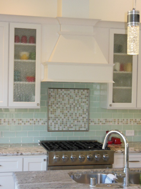 This is an example of a medium sized traditional l-shaped kitchen/diner in San Diego with a submerged sink, shaker cabinets, white cabinets, engineered stone countertops, green splashback, metro tiled splashback, stainless steel appliances, porcelain flooring, an island and white floors.