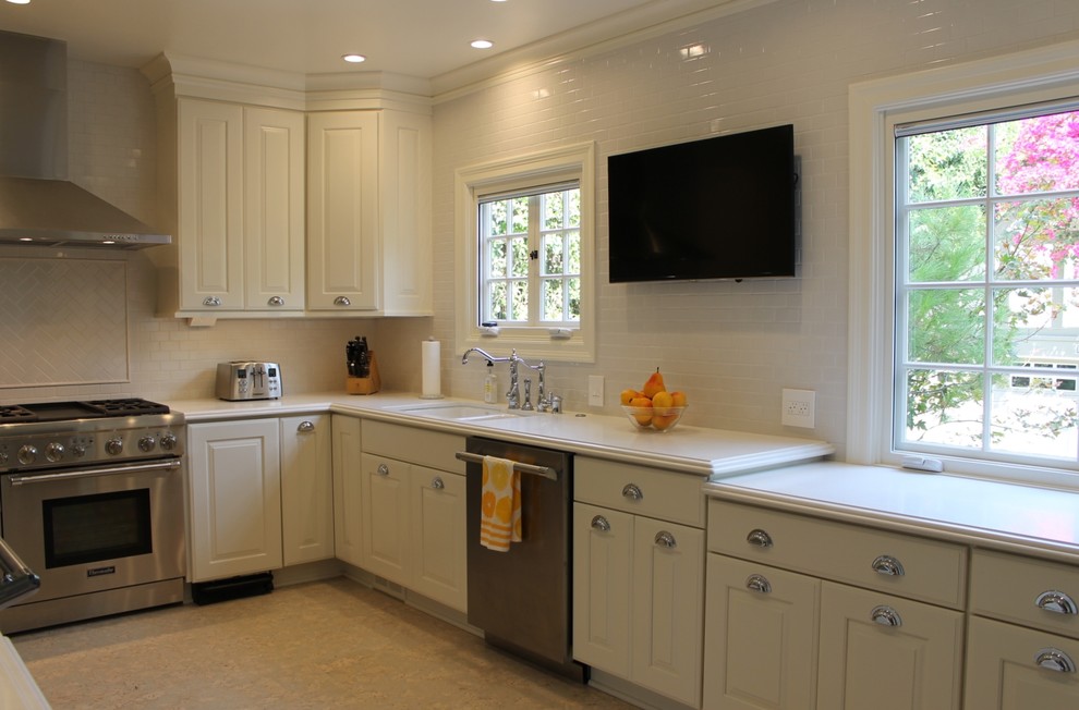 Bild på ett stort vintage kök, med en dubbel diskho, luckor med upphöjd panel, vita skåp, bänkskiva i kvarts, vitt stänkskydd, stänkskydd i keramik, rostfria vitvaror, korkgolv och vitt golv